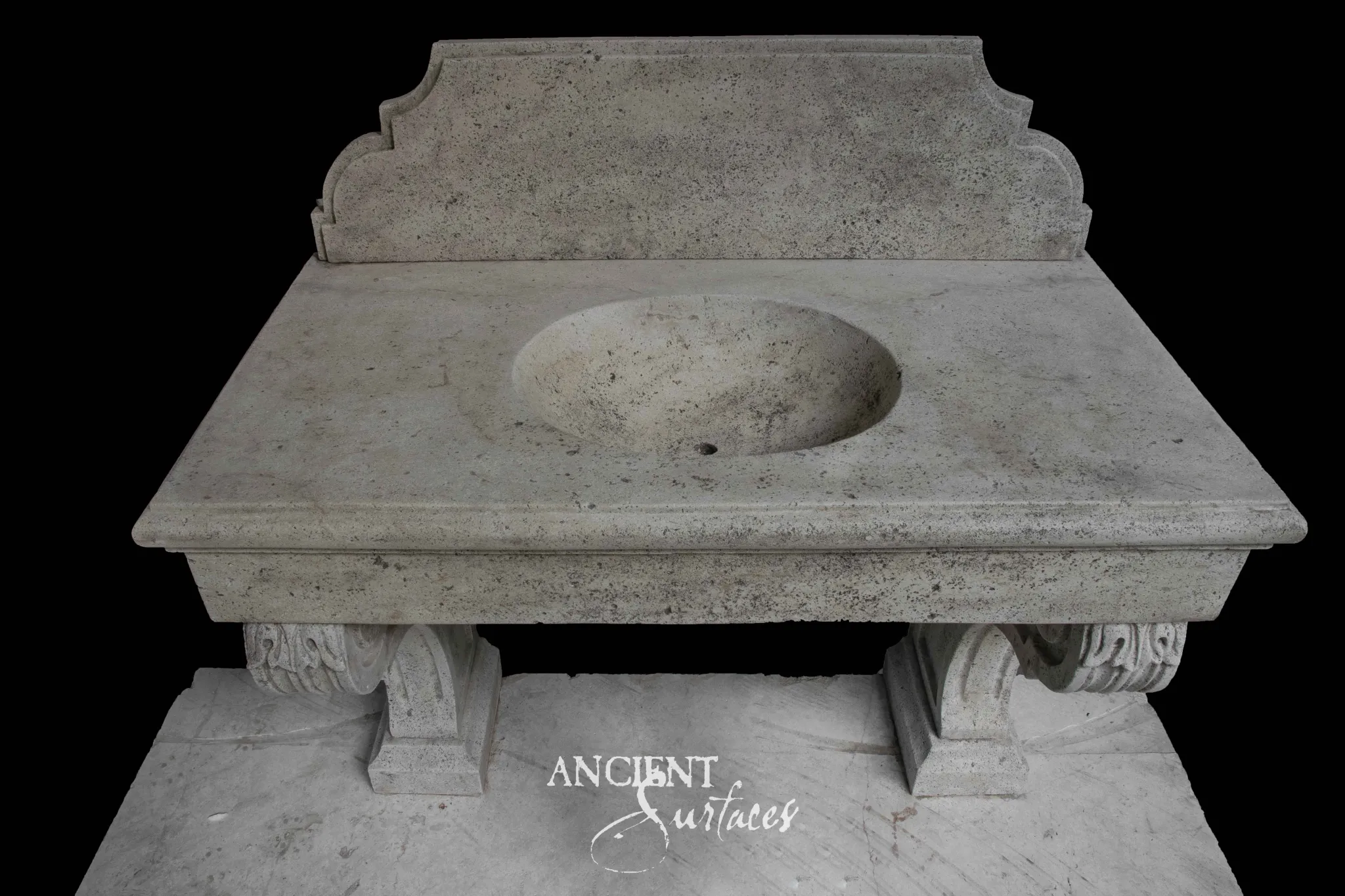 Grey reclaimed limestone console sink with a dished round basin, shaped arched backsplash and two carved leaf scroll legs