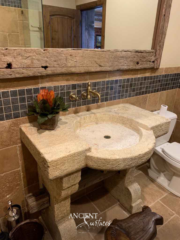 Sandy gold reclaimed limestone vanity sink with a stepped lobed top, shallow oval basin and raised kerb on two shaped stone supports